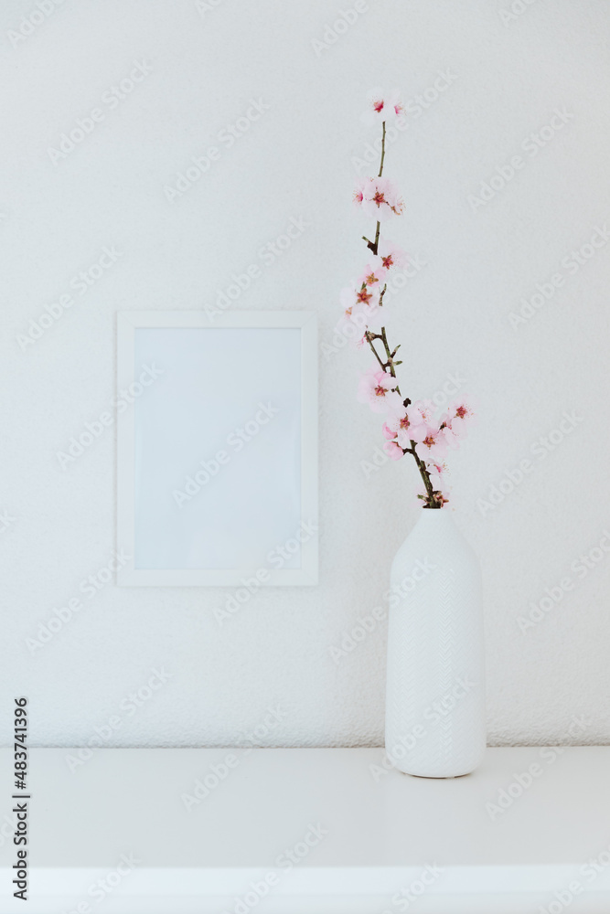 Almond blossom branches in a vase with picture frame mockup. White background, copy space.