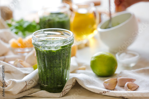 Jar of pesto sauce and ingredients on light background