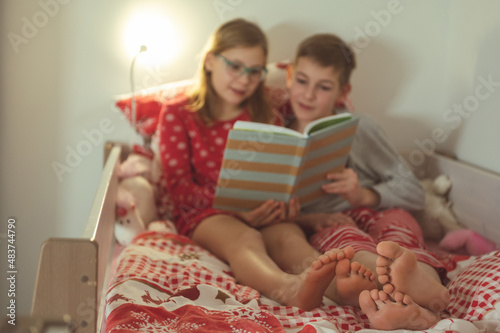 Tableau sur toile Teen brother and sister reading book in bed