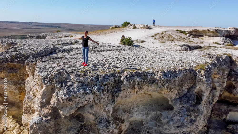 Fototapeta premium Girl poses standing at the edge on top of the White Rock Ak Kaya on the Crimea.
