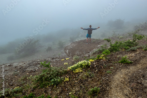 A man tourist on a rock admires the Demerdzhi mountain range on the Crimean peninsula.