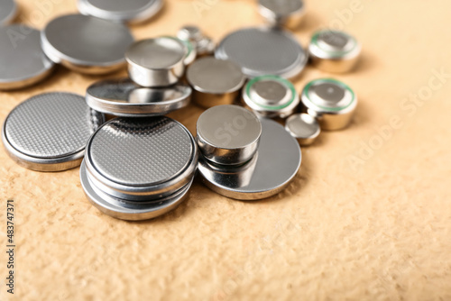 Lithium button cell batteries on beige background, closeup photo