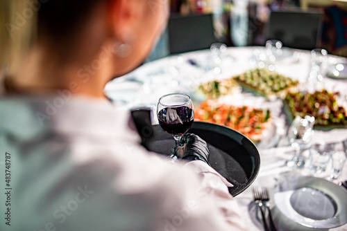 Waiter holding tray with red wine glass. Restaurant service