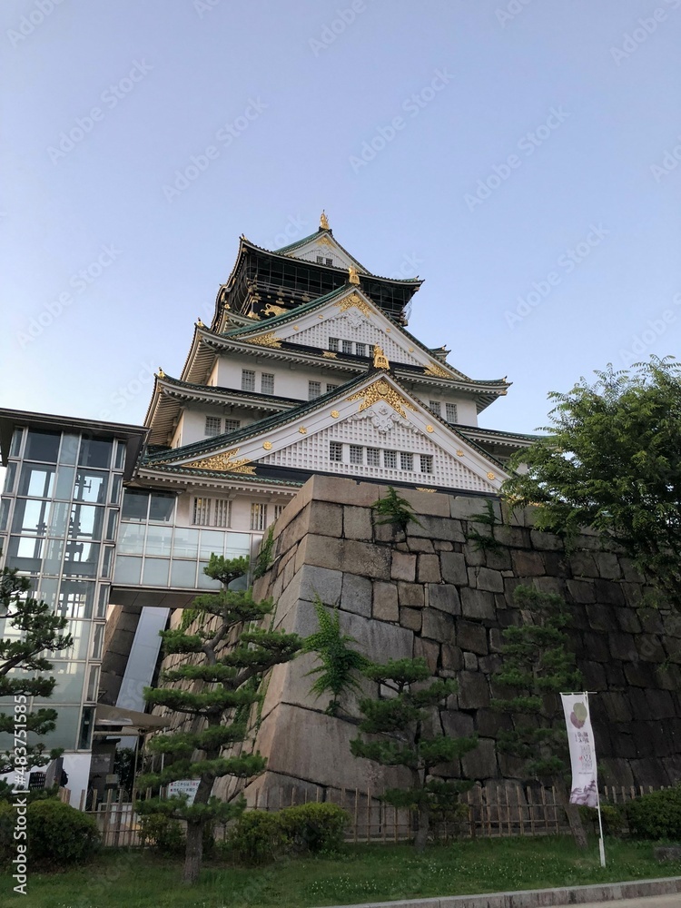 A famous historical sightseeing spot in Japan Osaka Jo castle with a modern elevator above the stone wall in the park in summer under the blue sky taken from the low angle A famous historical sightseeing spot in Japan Osaka Jo castle with a modern elevator above the stone wall in the park in summer under the blue sky taken from the low angle