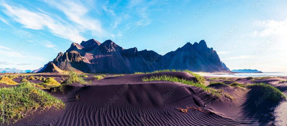 Scenic landscape with most breathtaking mountains Vestrahorn on the Stokksnes peninsula and cozy lagoon with green grass on the sand dunes in Iceland. Exotic countries. Amazing places.