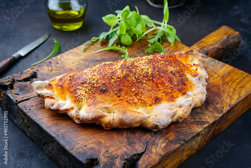 Fotografie Traditional Italian pizza calzone with tuna fish and onions served as close-up o