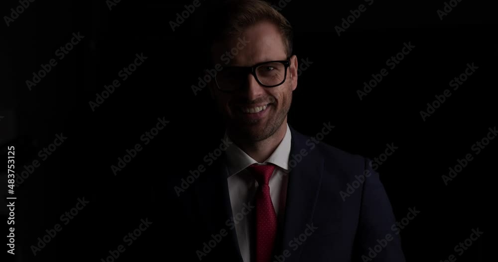 handsome businessman wearing eyeglasses, smiling at the camera on dark background handsome businessman wearing eyeglasses, smiling at the camera on dark background