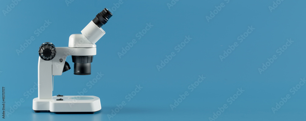 scientific microscope on blue background with space for text