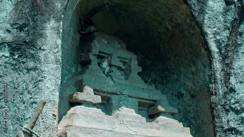 monkey sits in an old stone town at a stone gate and eats fruit