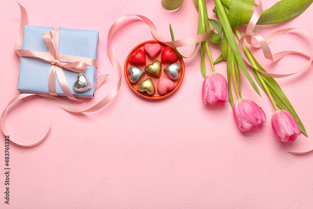 Composition with tasty heart-shaped candies and flowers for Valentine's Day celebration on pink background