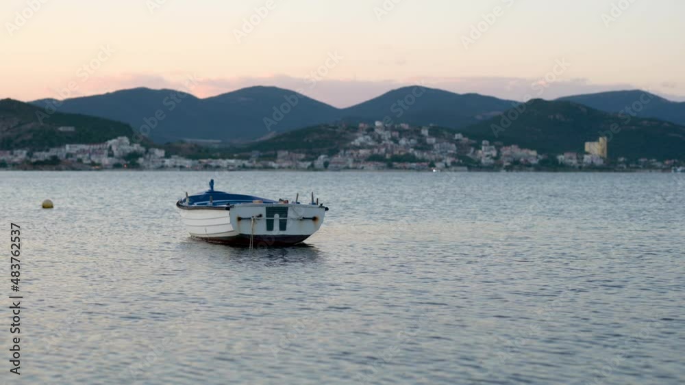 View of the rowboat lies in the calm sea at sunset. Wooden boat on the evening sea surface. View of the rowboat lies in the calm sea at sunset. Wooden boat on the evening sea surface.