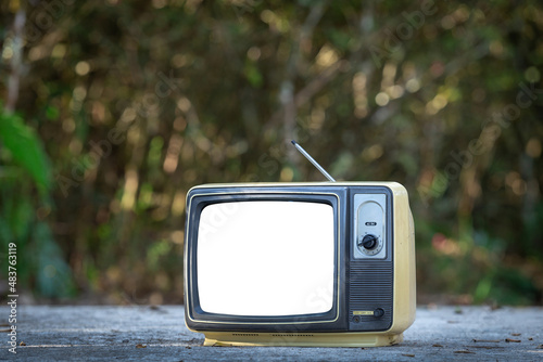 Retro old TV with white screen on cement floor with blurry forest background. photo