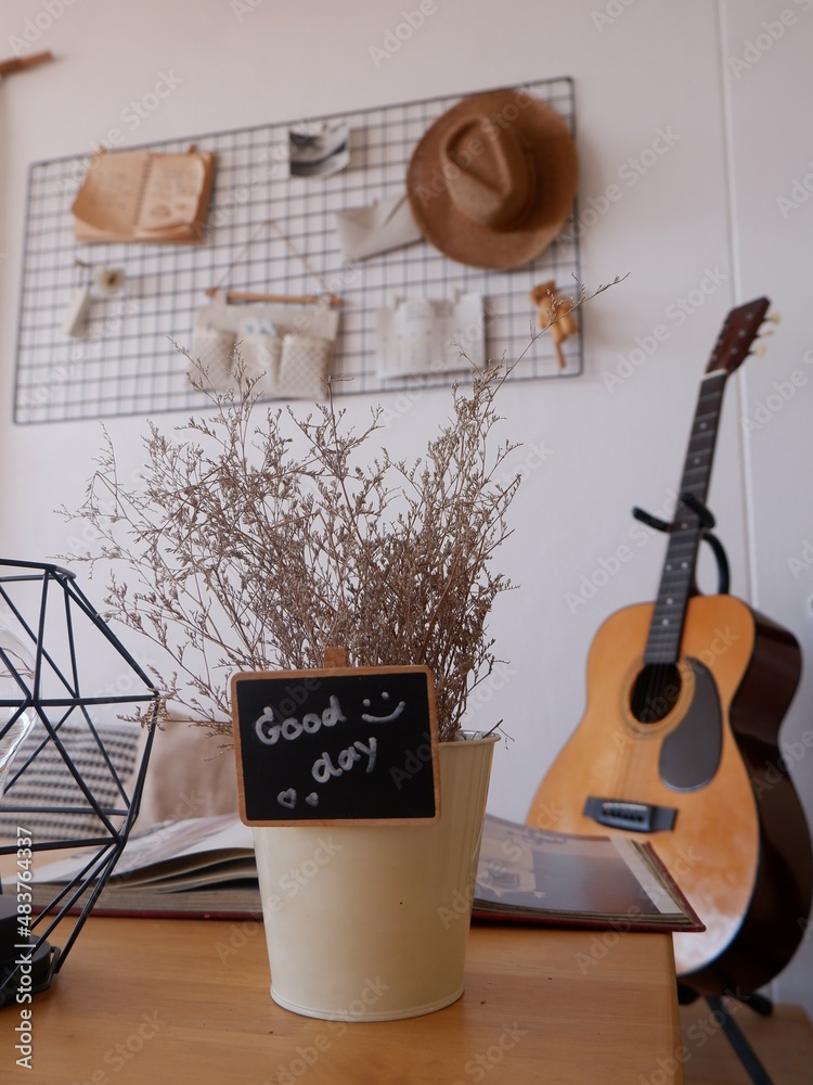 One part of decoration of coffee house with dry flower on table and wooden guitar