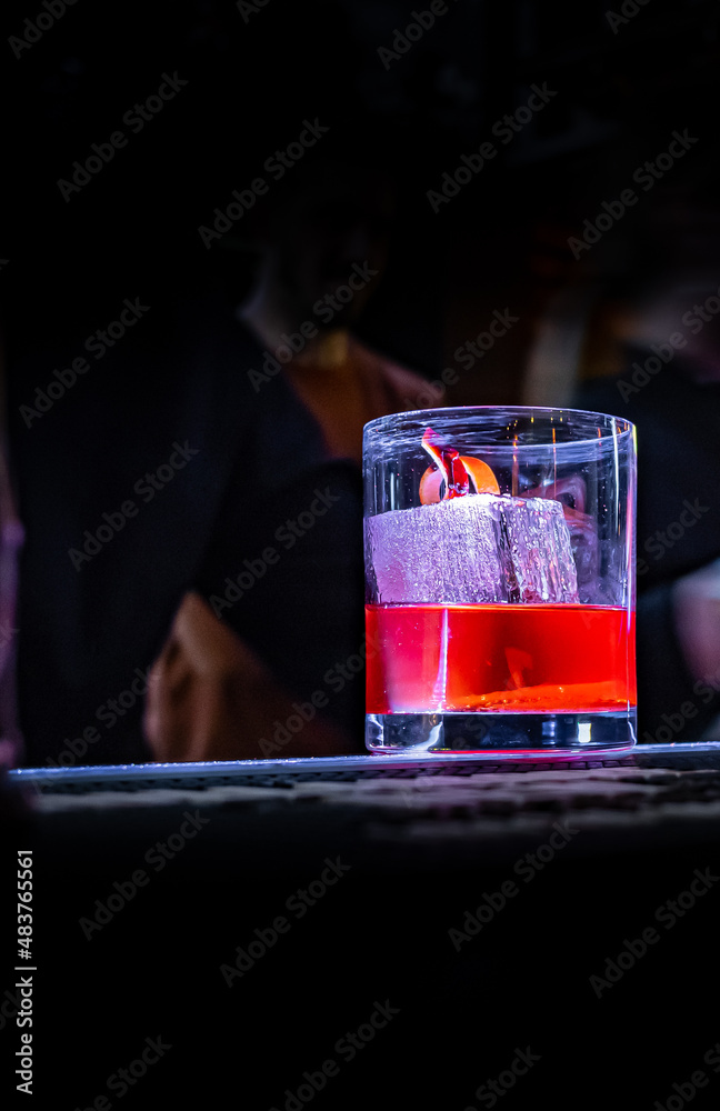 Cocktail Negroni with gin, campari martini rosso and orange in glass on bar  counter Photos | Adobe Stock