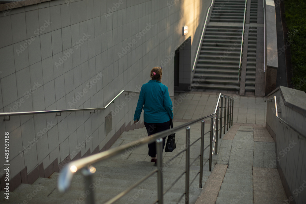 Woman walks up stairs. Pedestrian crossing. Descent to tunnel. Townsman descends steps.