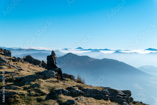 Pessoa no alto da montanha de La Rhune a descansar e admirar o mar de nuvens ao fundo photo