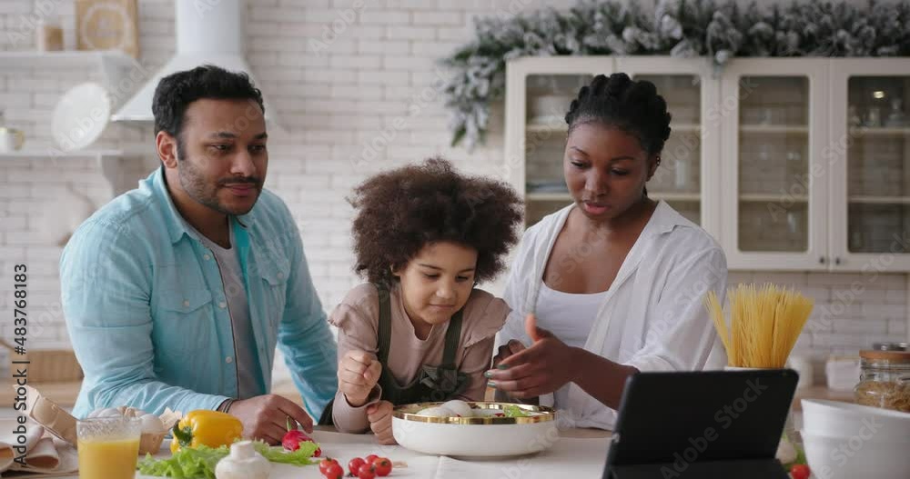 Mother and daughter cook according to recipe with dads help