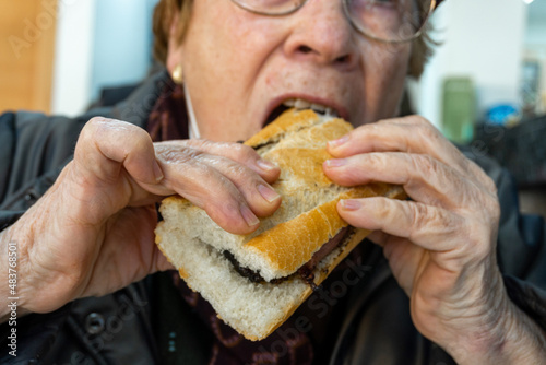 Senior woman biting into a sandwich