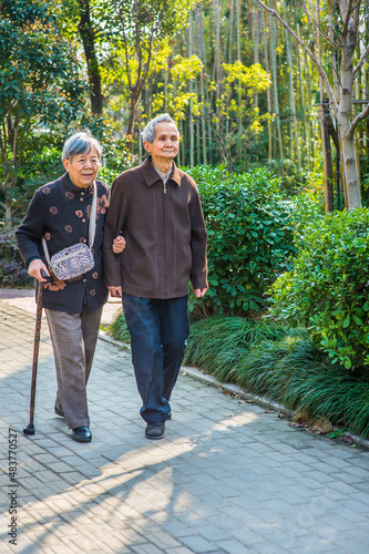 Obraz na płótnie Senior Man and Woman Walking Outside. A senior couple, 80 years old, helping each other, is walking outside, woman holding a walking stick.. w salonie