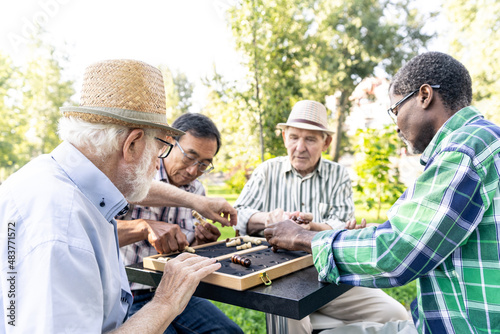 Group of senior friends playing chess at the park. Old multiethnic friends making activities outdoor. Concept about third age and lifestyle © oneinchpunch