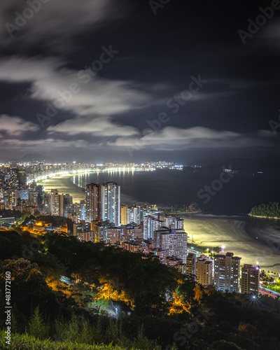 Vista do alto de noite com uma cidade a beira mar