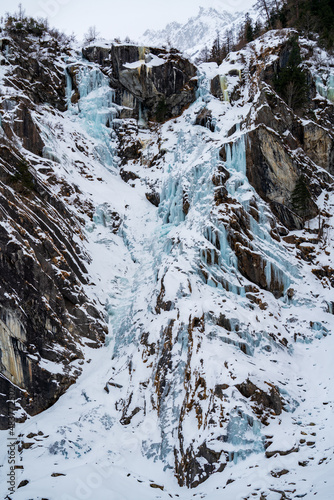 frozen waterfall in the alps hanging from the rocks ata cold winter day