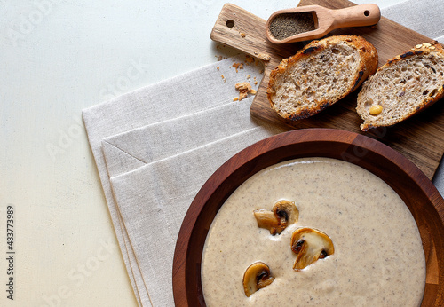 Creamy Mushroom Soup on wooden bowl on napkin, wooden background photo