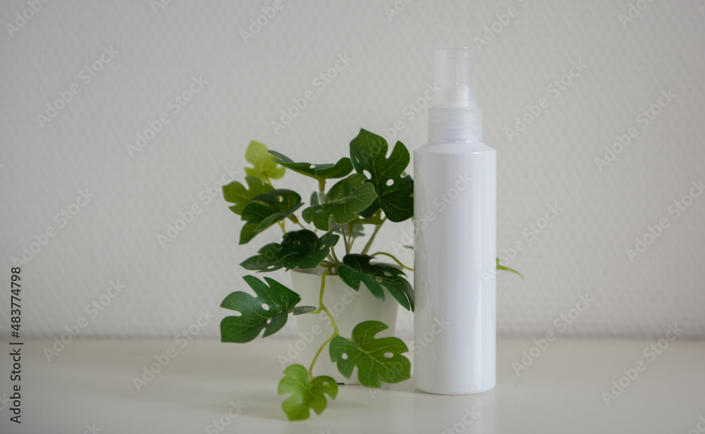 Flacon blanc devant un mur blanc avec une plante verte - mock up pour pouvoir y insérer texte et design - produit cosmétique Flacon blanc devant un mur blanc avec une plante verte - mock up pour pouvoir y insérer texte et design - produit cosmétique