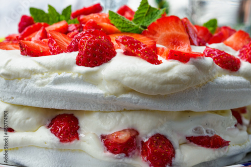 Side view of strawberry cake garnished with mint leaves.