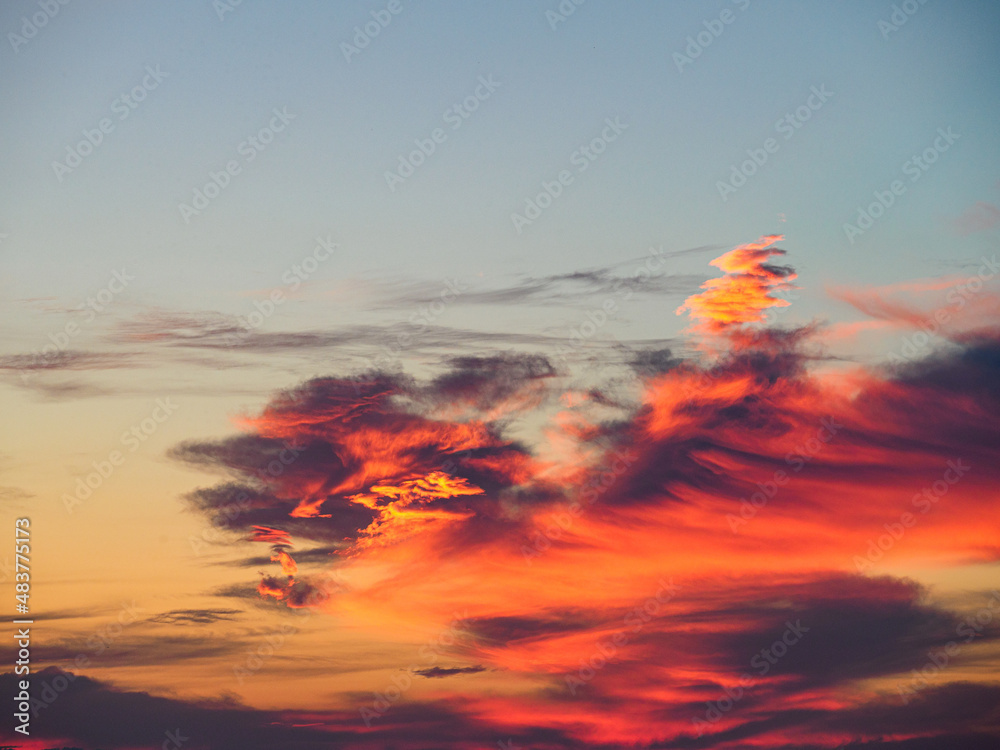 Lovely golden and pink clouds in sky with soft haze on sunset as abstract background, texture.