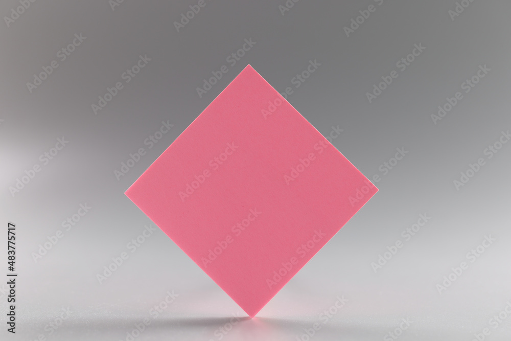 Pink blank paper rhombus on gray background, notepad