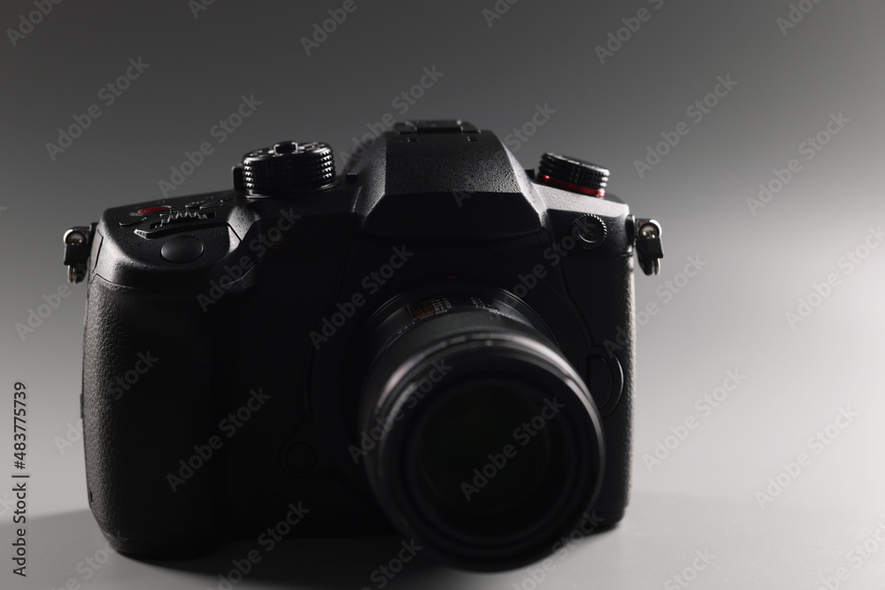 Black photo camera on a gray background, lens