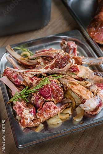 Rack of Lamb, raw, prepared for grilling. Blanks for restaurant and catering, with a sprig of rosemary on top.