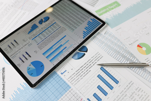 On statistical reports lies a tablet with charts on the screen photo