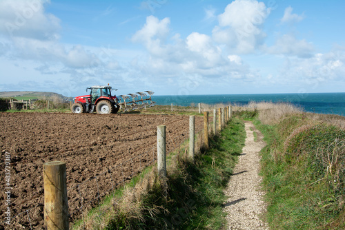 October 2019 - A farmer ploughs his field on a coastal farm at Trevose Head in Cornwall, UK photo
