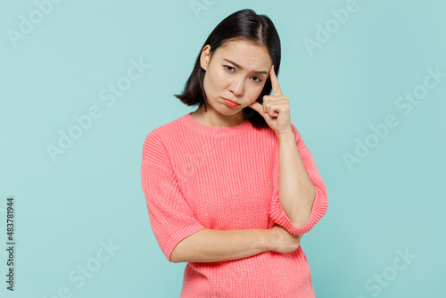 Young mistaken puzzled thoughtful unhappy woman of Asian ethnicity 20s in pink sweater look camera prop up head forehead isolated on pastel plain light blue background studio People lifestyle concept