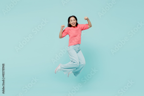 Fototapeta Naklejka Na Ścianę i Meble -  Full body young excited happy woman of Asian ethnicity 20s wearing pink sweater jump high do winner gesture isolated on pastel plain light blue background studio portrait. People lifestyle concept