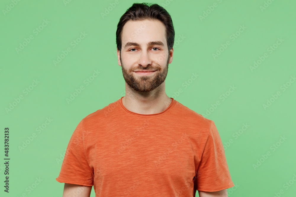 Young smiling happy cheerful positive european caucasian man 20s wearing basic casual orange t-shirt isolated on plain pastel light green color background studio portrait. People lifestyle concept Young smiling happy cheerful positive european caucasian man 20s wearing basic casual orange t-shirt isolated on plain pastel light green color background studio portrait. People lifestyle concept