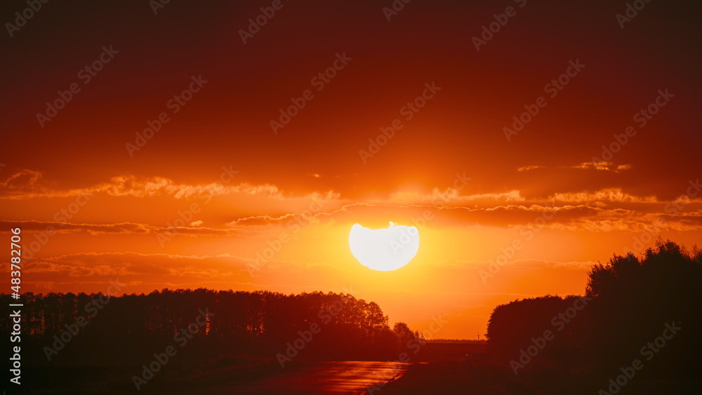 Big Sun in Vivid Beautiful Sunset Sunshine Above Summer Landscape Counrty Road And Forest. Sunset Sunlight. Forest shadow, silhouette Landscape. Country Road . Big Sun in Vivid Beautiful Sunset