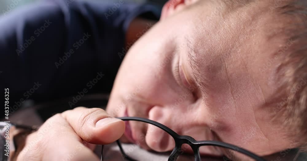 Young man sleeping at table among folders with documents and holding glasses in hands 4k movie Young man sleeping at table among folders with documents and holding glasses in hands 4k movie