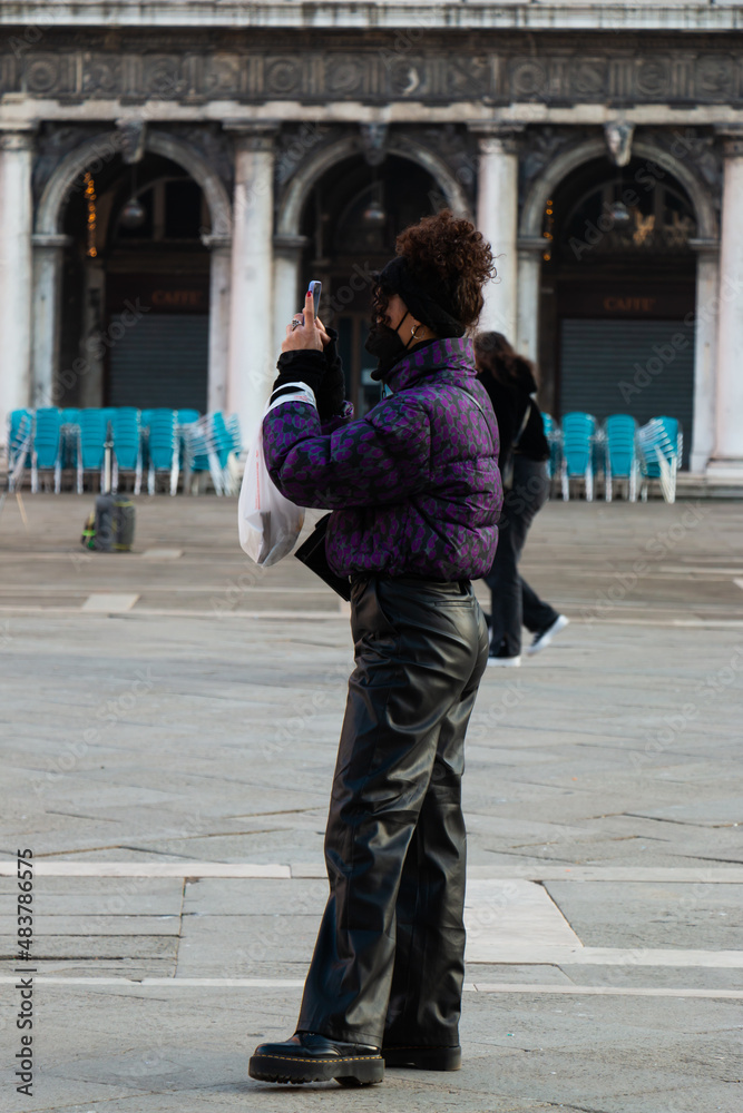 Naklejka premium A young woman in black faux leather pants and a black and purple jacket.