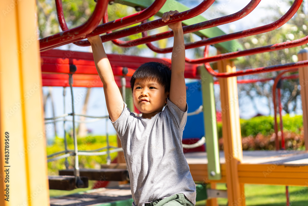 Fototapeta premium Asian kid plays in the outdoor playground. Concept of learning outdoor and happiness