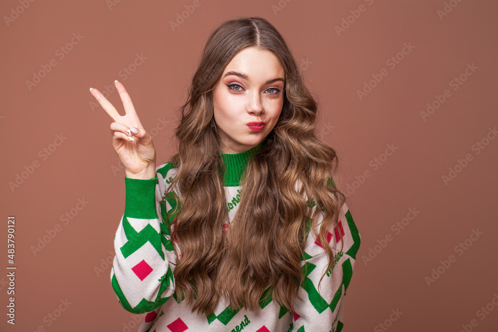 Fototapeta premium Portrait of a young beautiful teenage girl on a beige isolated background