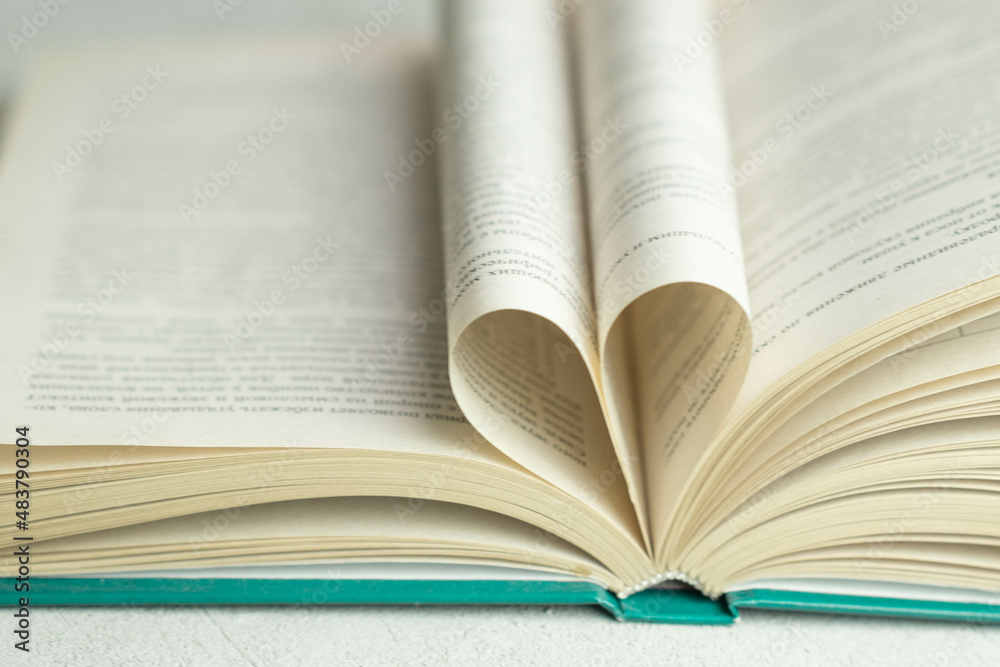 Obraz premium an open book with folded pages in the shape of a heart , the concept of Valentine's day, blurred background