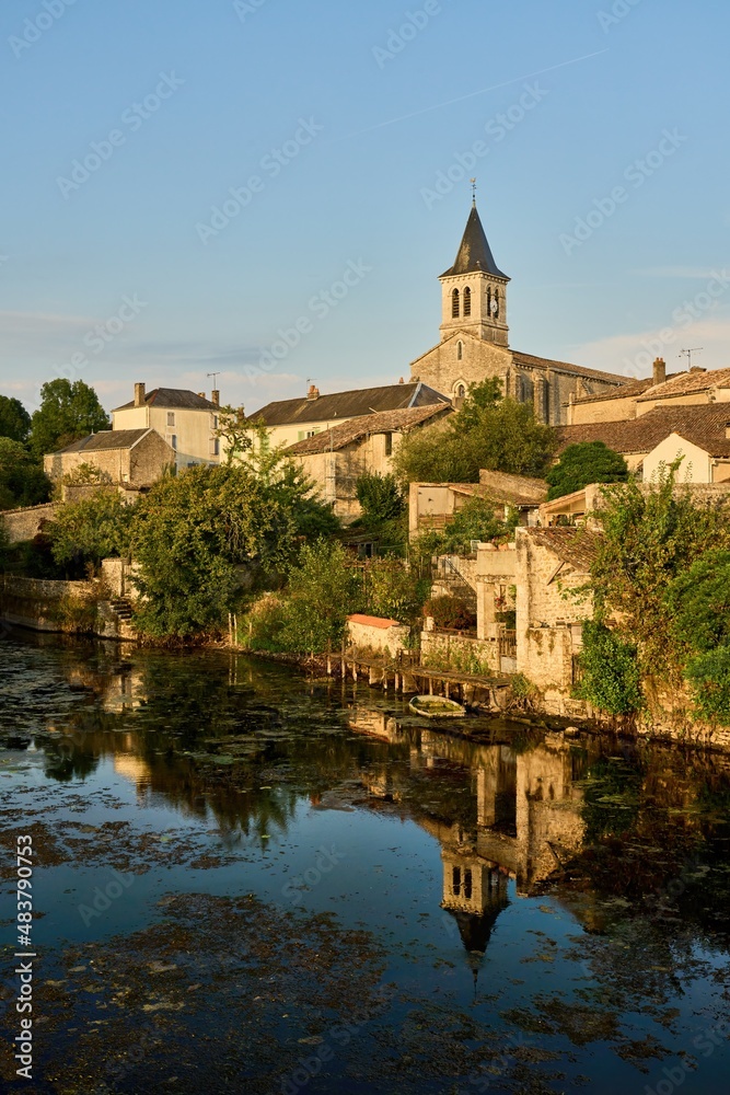the church of Sanxay and the medieval arched stone bridge are reflected in the water surface of the river Vonne