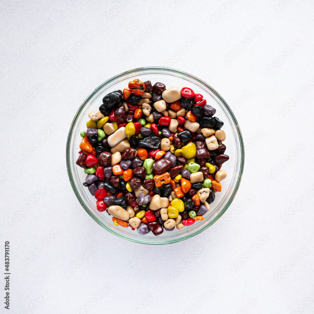 Sweets in a glass plate on a white background. Multicolored sea stones Sweets in a glass plate on a white background. Multicolored sea stones
