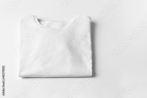 Basic folded white Tshirt on grey table with copy space. Mock up for branding t-shirt. Monochrome trend. 