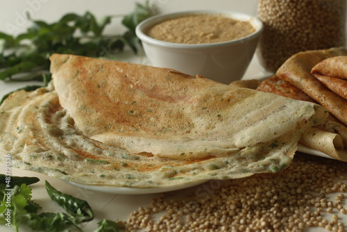 Jowar Dosa. A savoury crepe made of jowar flour. Golden crispy and crunchy dosa made with jowar flour, onion, cumin seeds, ginger, green chili and coriander leaves served with spicy coconut condiments