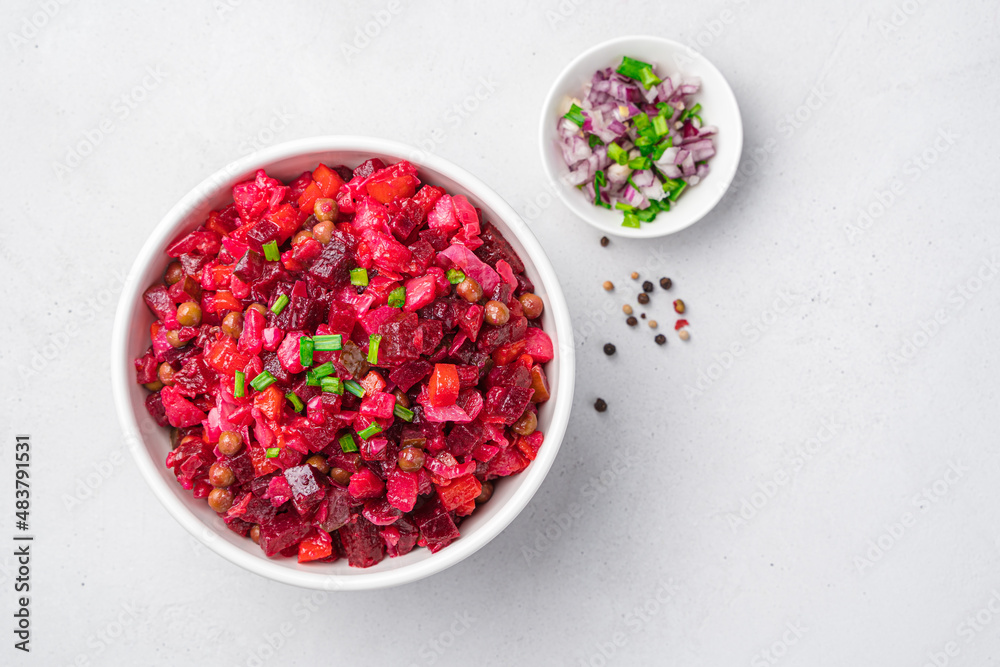 A bowl with beetroot vegetable salad on a gray background with onions and herbs. A bowl with beetroot vegetable salad on a gray background with onions and herbs.