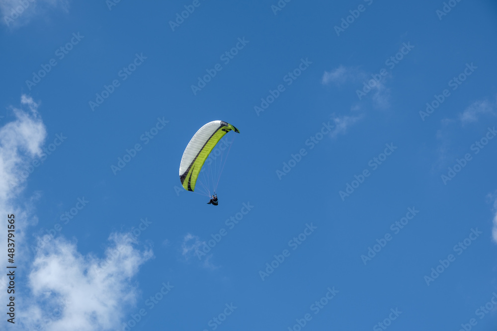 Paragliding pilot in the air with blue sky and white clouds, near the Wasserkuppe nature park Rhön Germany. Paragliding pilot in the air with blue sky and white clouds, near the Wasserkuppe nature park Rhön Germany.